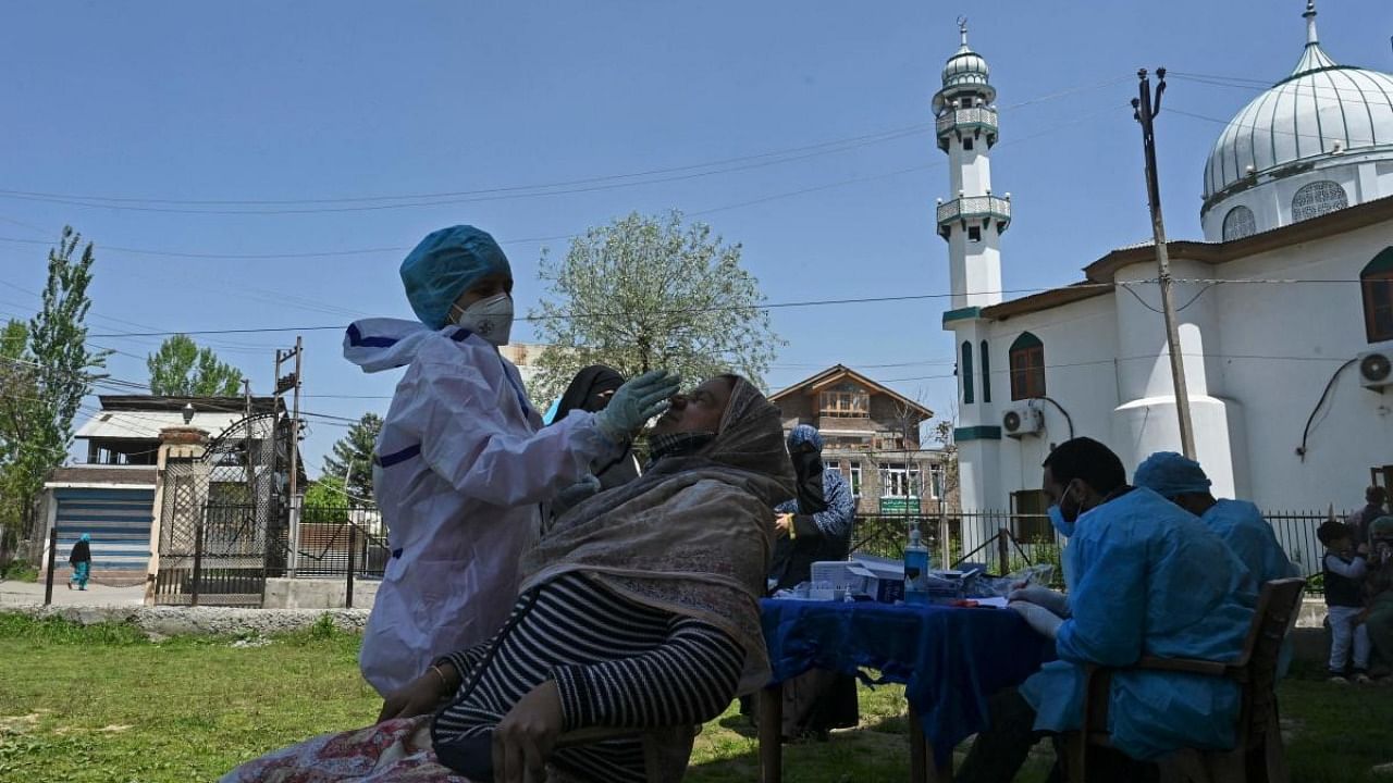 A health worker takes a nasal swab sample from a woman to test for the Covid-19 coronavirus at a testing center in Srinagar on April 27, 2021. Credit: AFP Photo