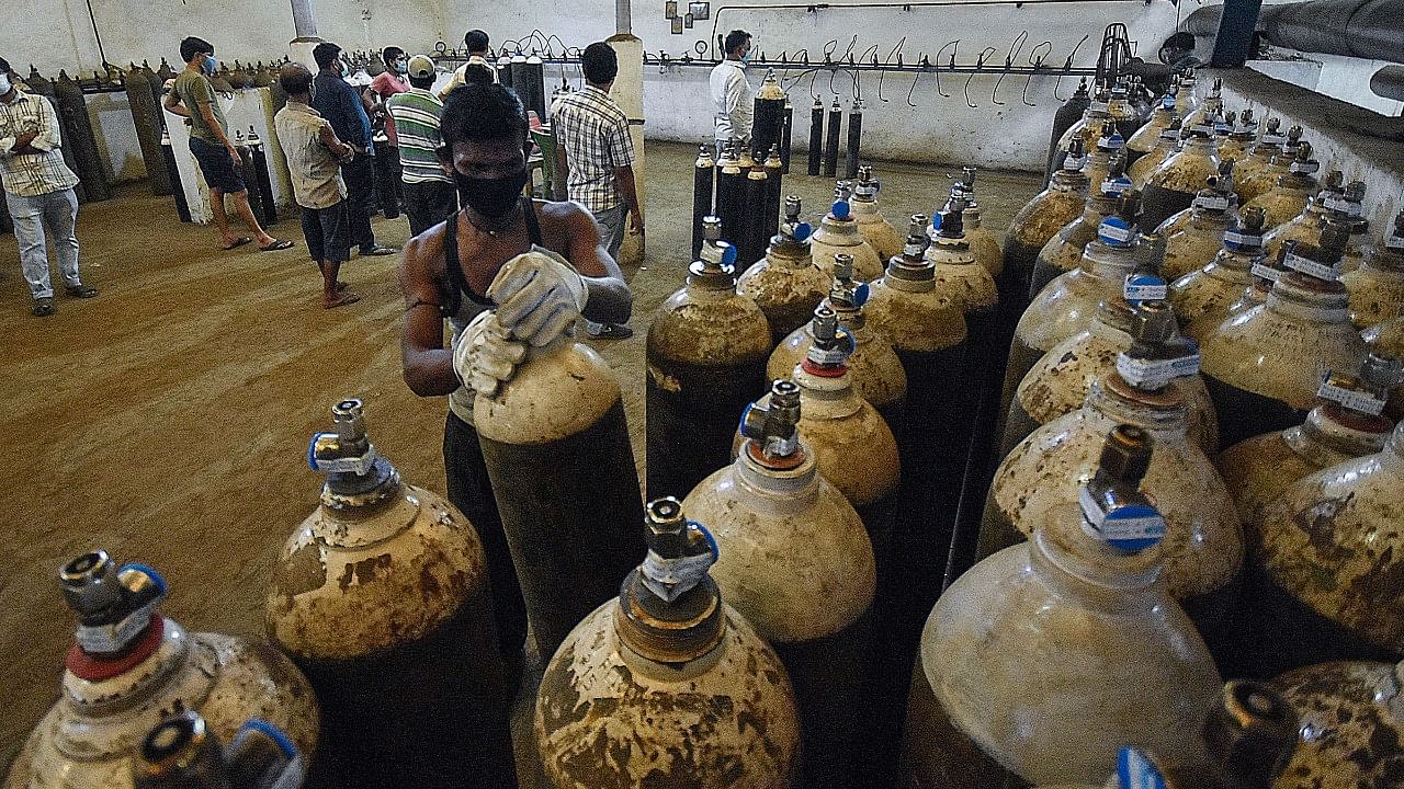 Worker adjusts oxygen cylinders at a refiling center. Credit: PTI Photo