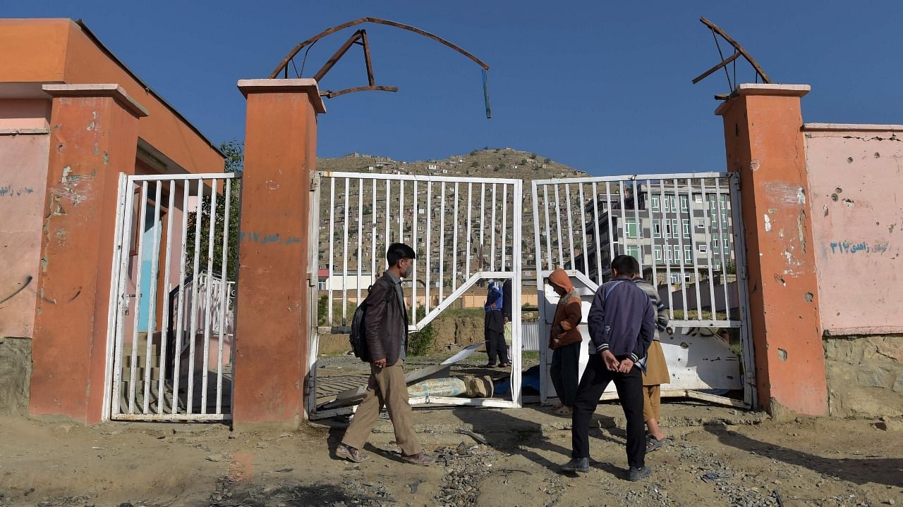 Onlookers stand near the site of Saturday's multiple blasts outside a girls' school in Dasht-e-Barchi on the outskirts of Kabul. Credit: AFP Photo