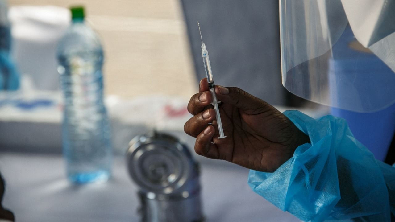 A health care worker at the Joseph Ravoahangy Andrianavalona Hospital shows a sample of the Oxford/AstraZeneca vaccine that will be administered to Ministry of Health personnel involved in the fight against the Covid-19 coronavirus in Antananarivo on May 10, 2021. Credit: AFP Photo