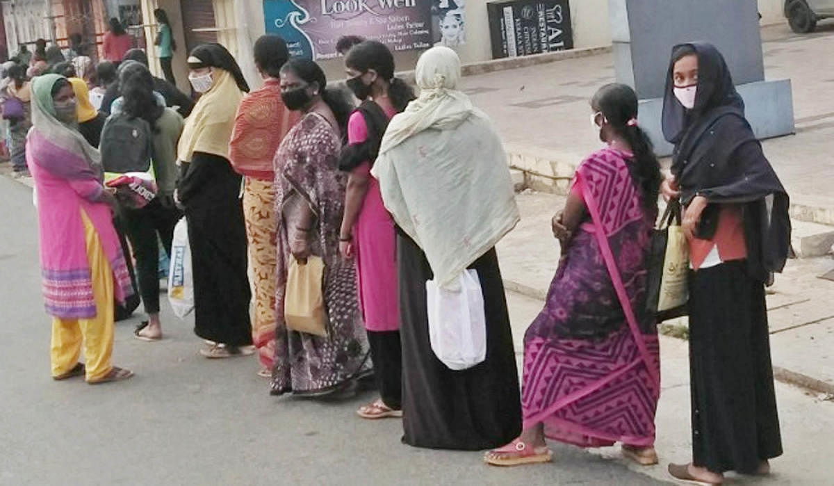 Ration card holders wait in a queue near a PDS in Gonikoppa.