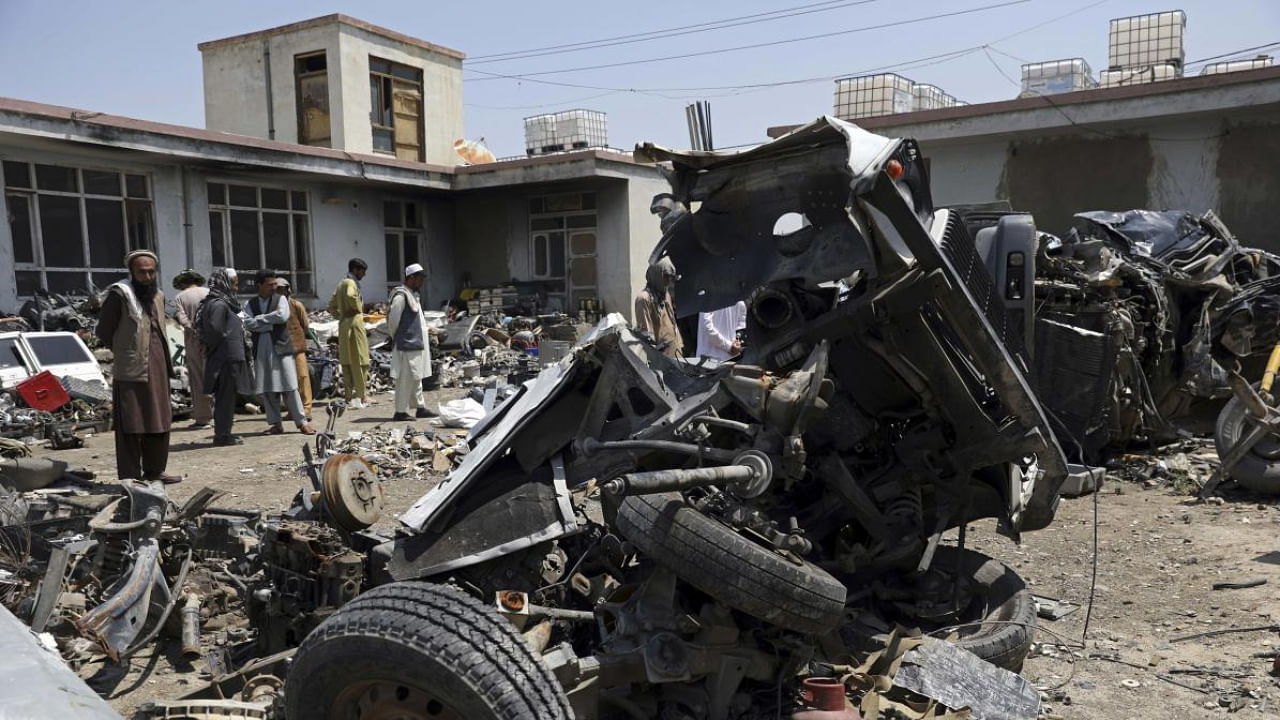 Afghans stand inside Baba Mir's scrapyard outside Bagram Air Base, northwest of the capital Kabul, Afghanistan. Credit: AP Photo