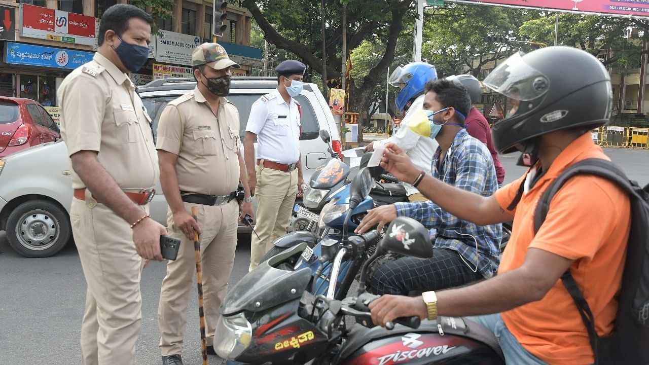 Police personnel intercept vehicles at Ramaswamy Circle, in Mysuru, on Monday, for violation of lockdown provisions. Credit: DH Photo