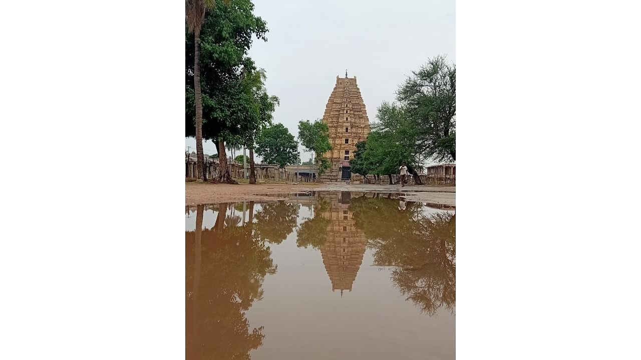 Reflection of the magnificent Bhistappaiah Gopura of Virupaksha Temple on a puddle of water following a spell of rain, in Hampi on Monday. Credit: DH Photo