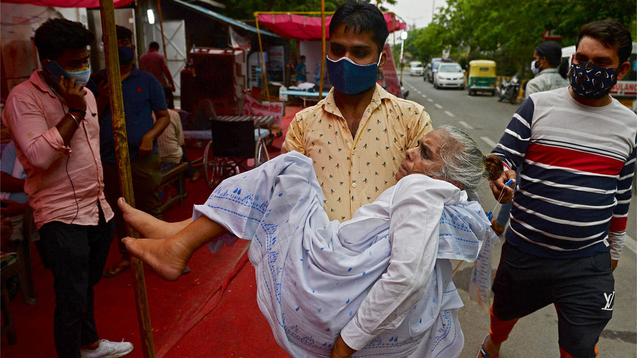 A family member carries a patient who is having difficulty in breathing, to a free oxygen support centre being run by a Gurudwara in Delhi. Credit: AFP Photo