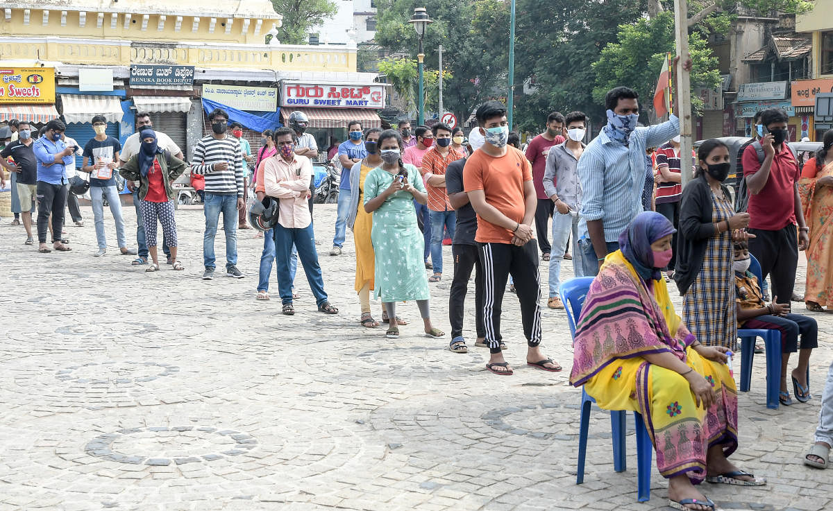 People wait in a queue to get tested for Covid in Mysuru.DH Photo