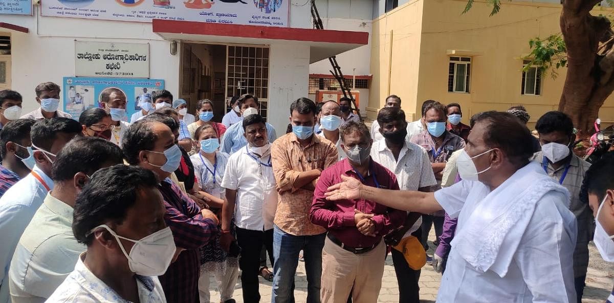 MLA K M Shivalinge Gowda pacifies the protesting employees to return to work, at the taluk hospital in Arsikere, Hassan dsitrict on Tuesday. DH Photo
