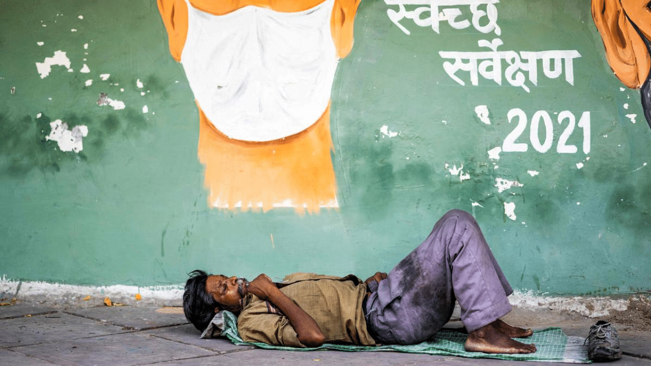 A man rests on a footpath under a coronavirus awareness painting in New Delhi. Credit: AFP Photo