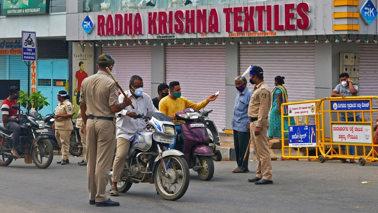 Police personnel stop commuters on a road for checking after a lockdown was imposed by the state government as a preventive measure against the spread of Covid-19. Credit: AFP Photo