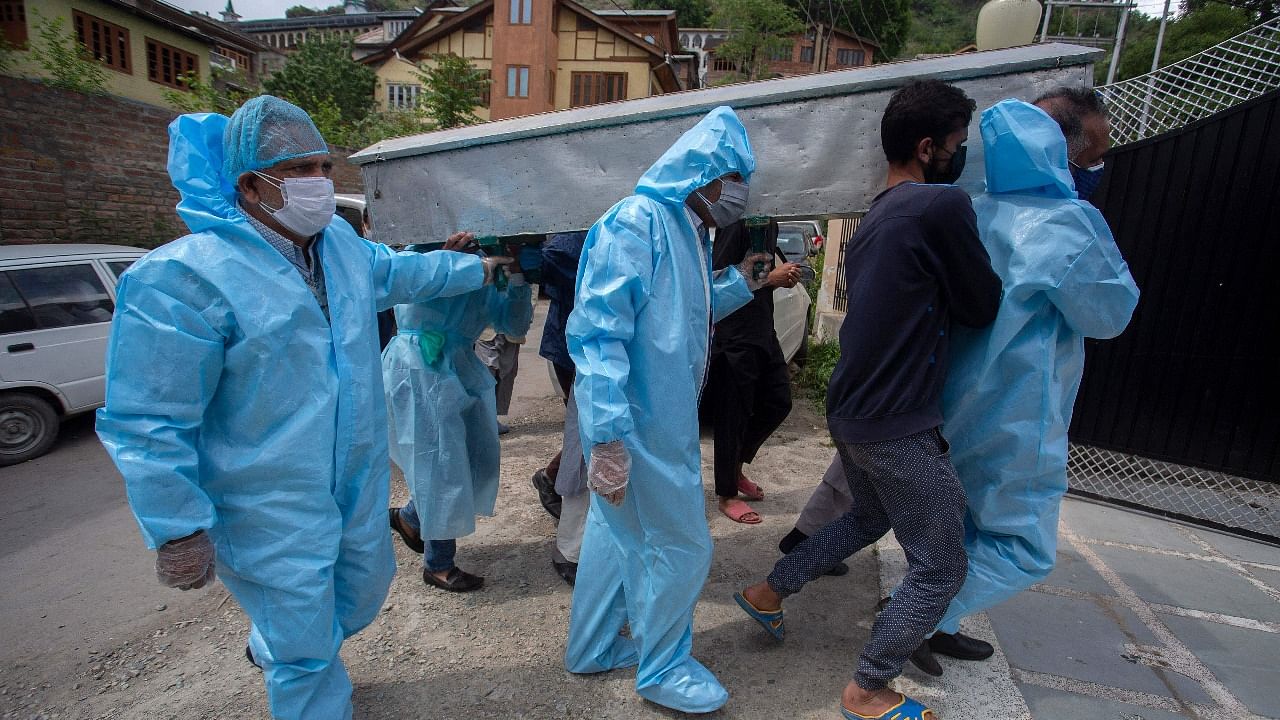 Relatives wearing protective gear carry the body of a victim who died of the Covid-19 coronavirus during the funeral procession in Srinagar. Credit: AFP Photo