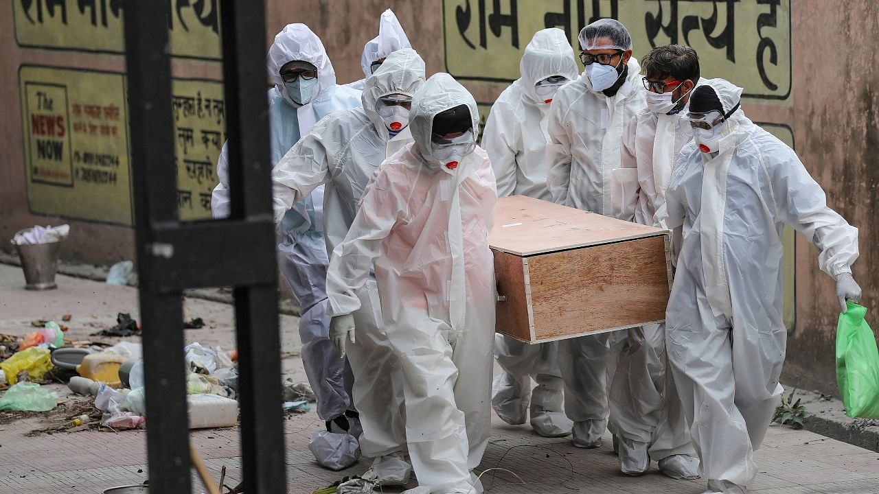 Health workers and family members, wearing protective suits, carry a Covid-19 victim for cremation, in Jammu. Credit: PTI Photo