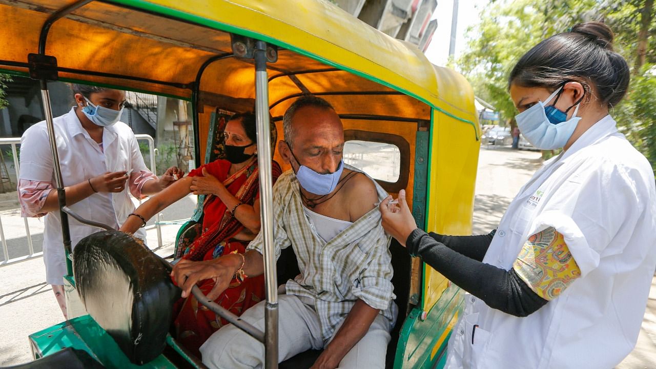 Health workers give a dose of Covid-19 vaccine to a man and a woman during drive through vaccination in Ahmedabad. Credit: PTI Photo