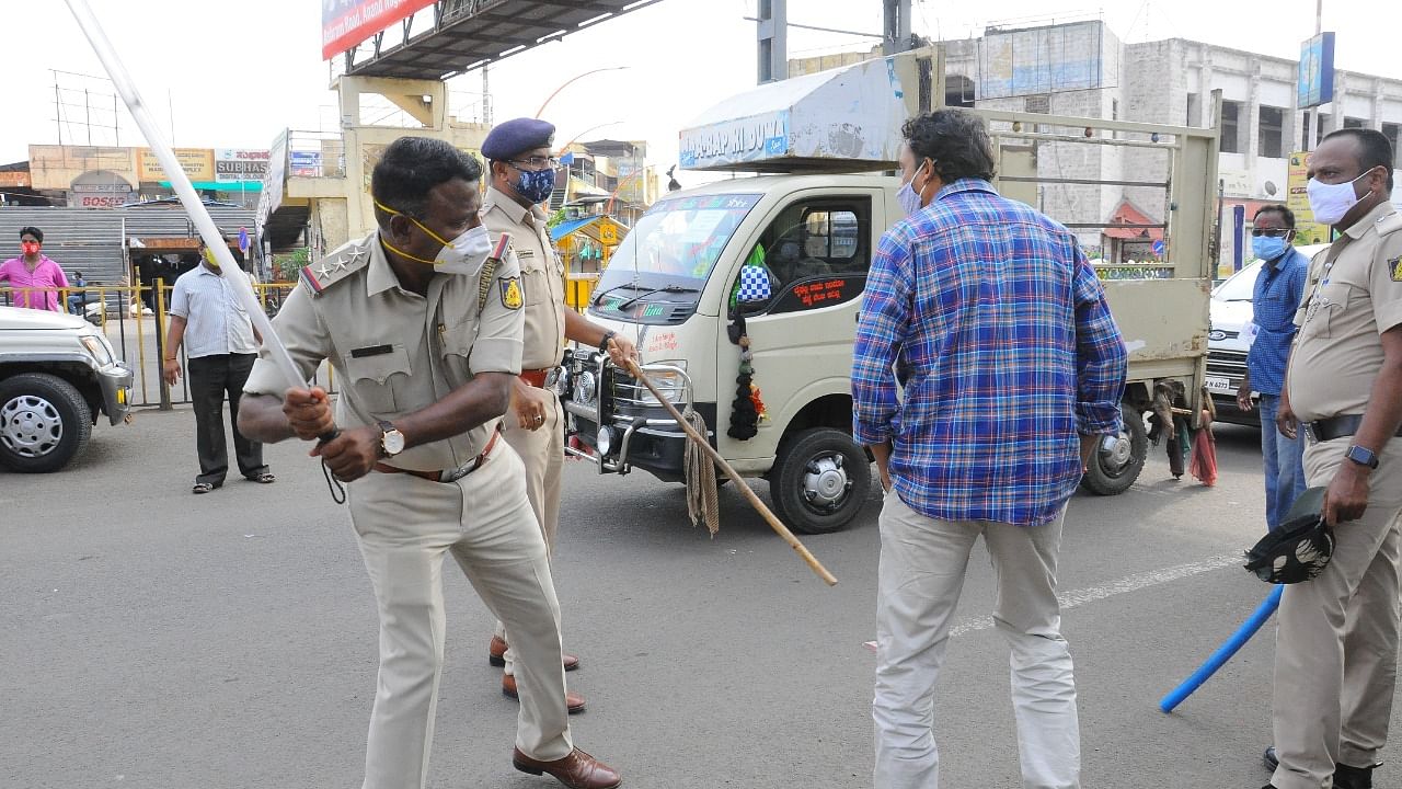 A policeman uses a lathi to enforce lockdown norms in Bijapur. Credit: DH Photo