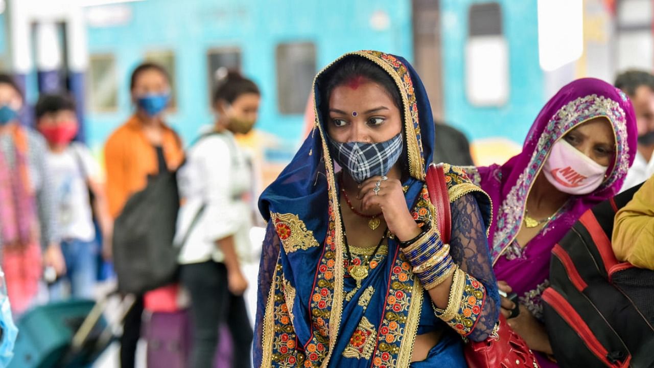 Passengers wearing face masks wait in a queue for Covid-19 test, at a Railway station in Jammu. Credit: PTI Photo