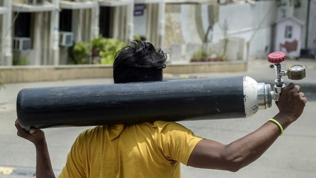 A family member of a Covid-19 patient carries oxygen cylinder for free refilling at Gurudwara Singh Sabha in Greater Kailash, New Delhi, Wednesday, May 12, 2021. Credit: PTI Photo