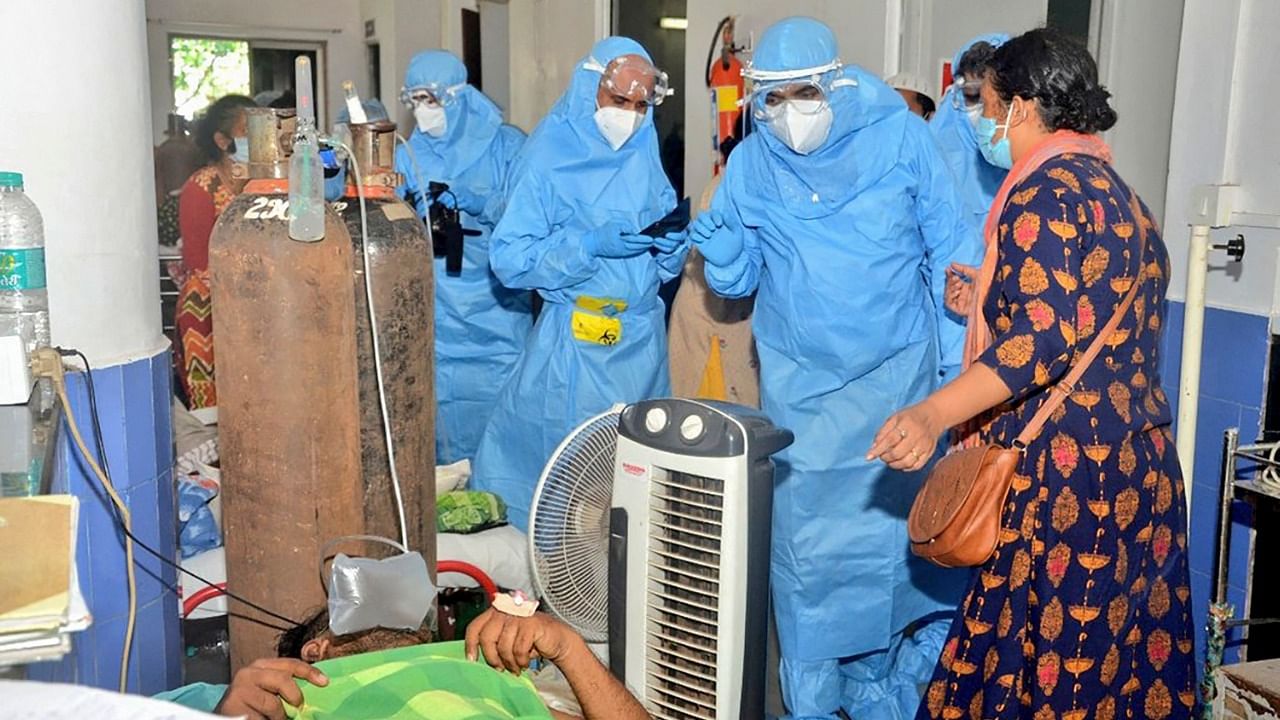 In this handout photograph released by Goa Chief Minister’s office and taken on May 11, 2021 Goa Chief Minister Pramod Sawant (R), wearing a personal protective equipment (PPE) suit, speaks to Covid-19 Coronavirus patients at the Goa Medical College and Hospital (GMCH), in Panjim after 26 people admitted in the hospital due to the coronavirus died on the early morning. Credit: AFP Photo