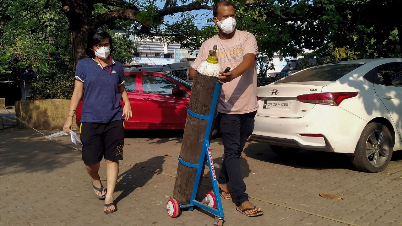 A couple walks with an oxygen cylinder for a Covid-19 coronavirus patient addmited at the Goa Medical College and Hospital (GMCH). Credit: AFP Photo