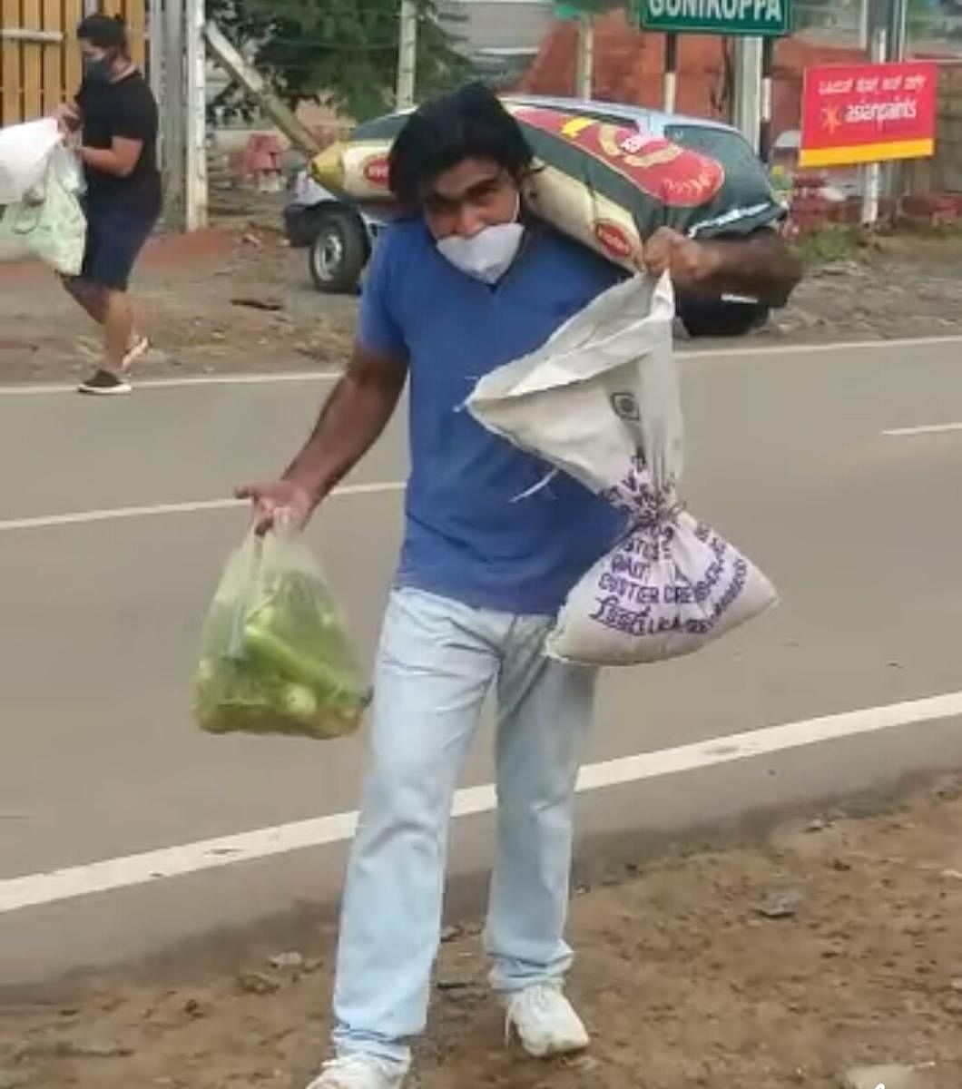 A man struggles to carry essential items and groceries in Gonikoppa.