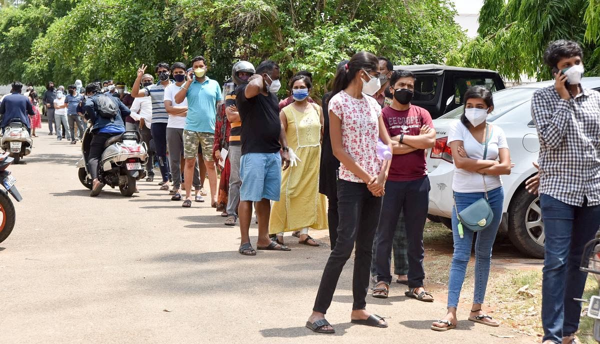 People queue up at the Covid vaccination centre on the premises of Ganabharathi on Adichunchanagiri Road in Kuvempu Nagar, Mysuru, on Thursday. DH Photo