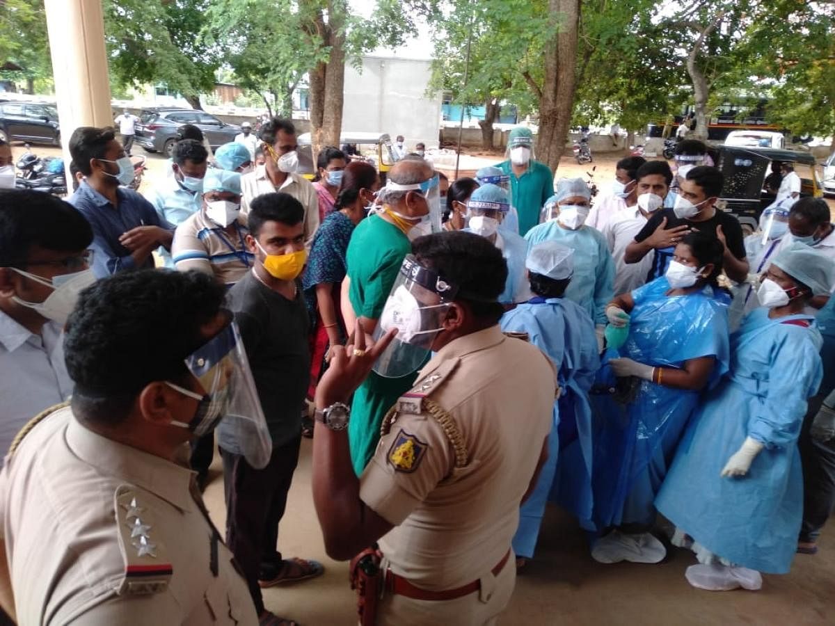 Police personnel pacify protesting relatives of a patient at the government taluk hospital in Gundlupet, Chamarajanagar district on Thursday. DH Photo