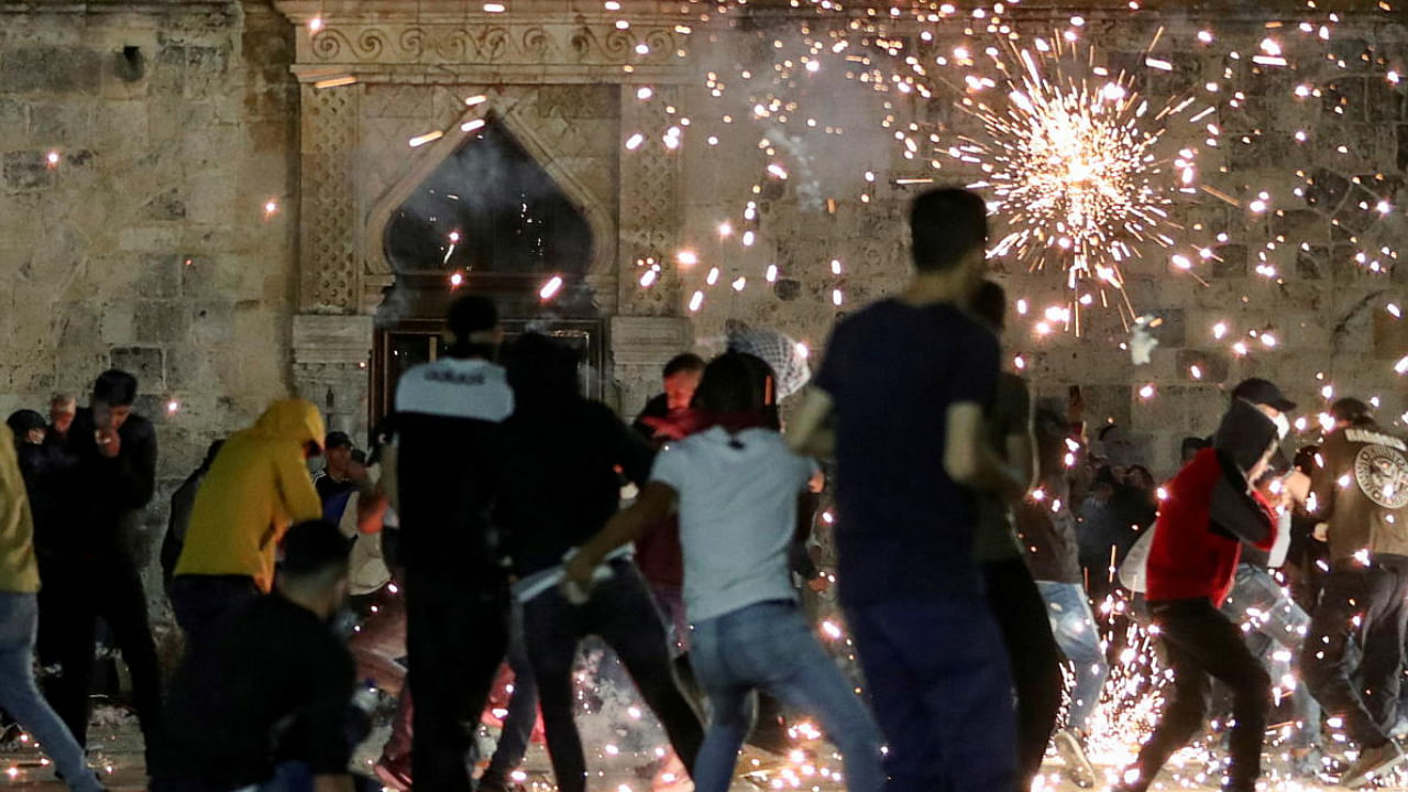 Palestinians react as Israeli police fire stun grenades during clashes at the compound that houses Al-Aqsa Mosque. Credit: Reuters Photo