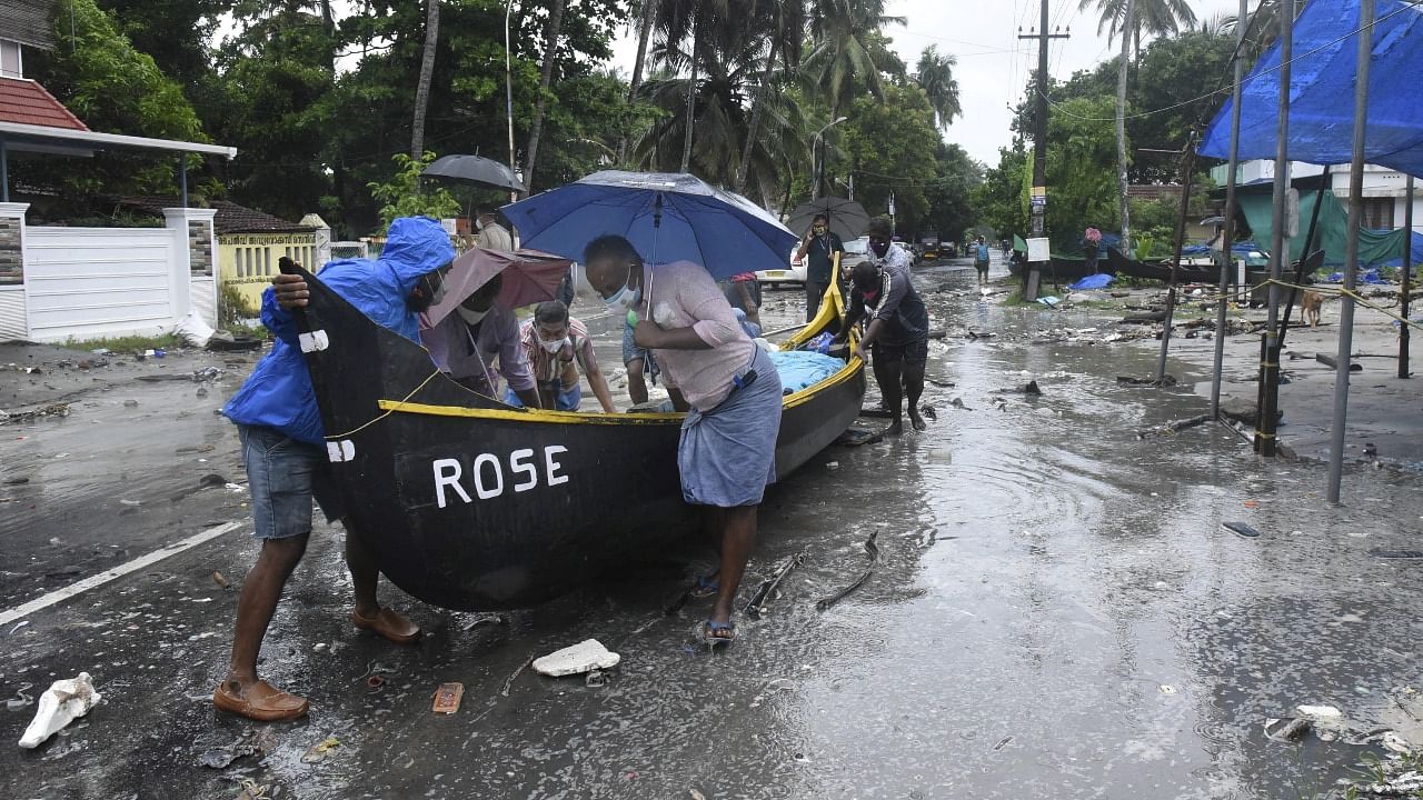 People shift a boat to safe place after it sailed away amid strong winds and heavy rains, owing to a cyclonic formation in the Arabian Sea, in Kochi. Credit: PTI Photo