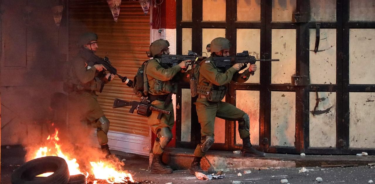 Israeli soldiers take aim during clashes with Palestinian protesters in the city center of Hebron. Credit: AFP Photo