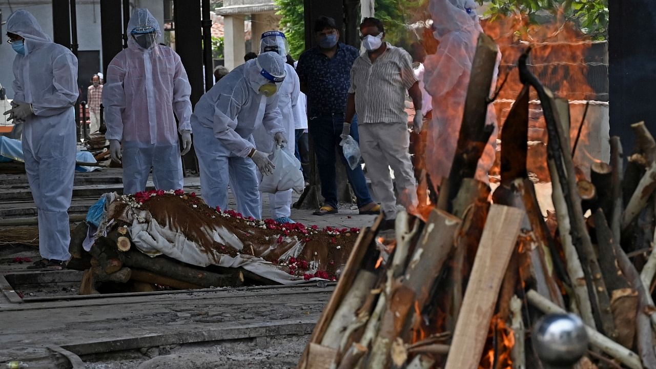 Relatives and family members wearing PPE suits perform the last rites of the patients who died of Covid. Credit: AFP Photo