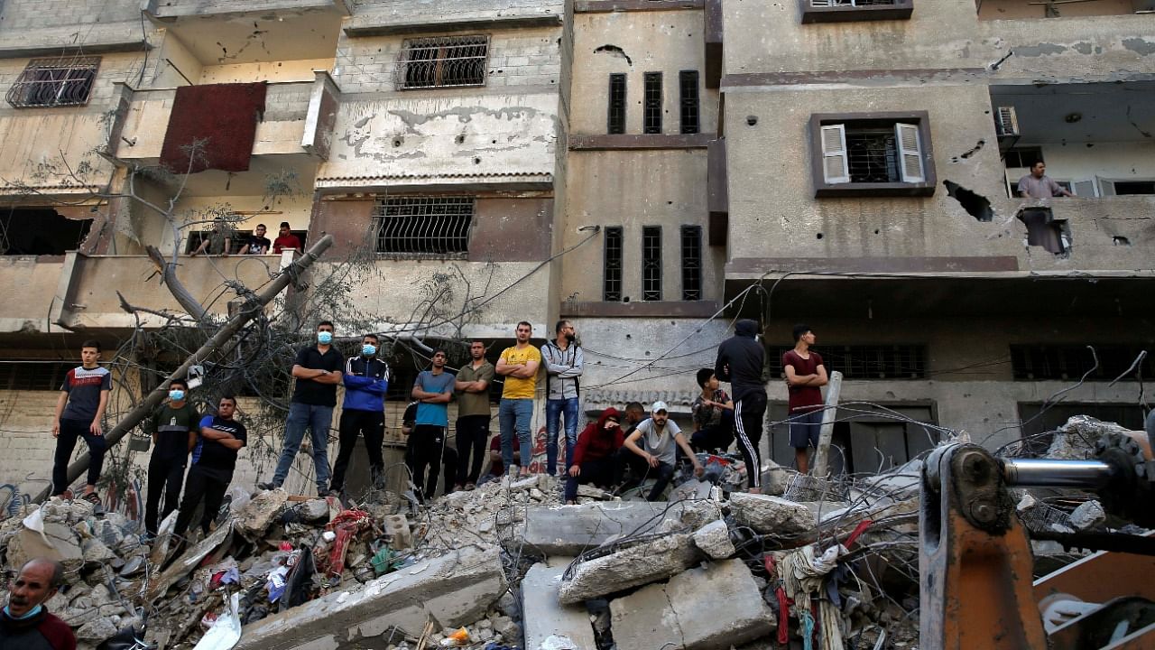 Palestinians gather as rescuers search for victims at the site of a destroyed house in the aftermath of Israeli air strikes, amid a flare-up of Israeli-Palestinian violence, in Gaza City. Credit: Reuters Photo