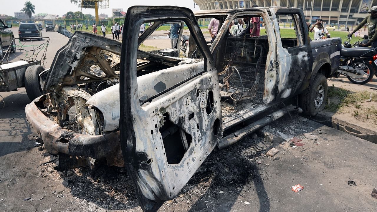 People inspect a burned police car, after two groups of Muslims clashed outside Martyrs Stadium in Kinshasa. Credit: Reuters photo