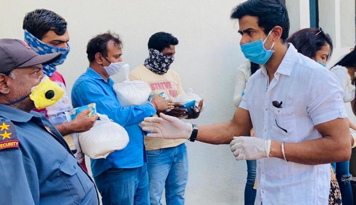 Actor Aryann Santosh distributes grocery kits to the needy. DH Photo