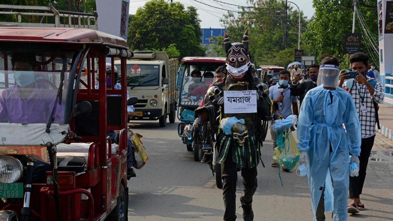 A volunteer dressed as Yamraj roams around the streets creating awareness to follow the Covid-19 safety protocols while also distributing face masks and hand sanitisers to people in West Bengal. Credit: AFP Photo.
