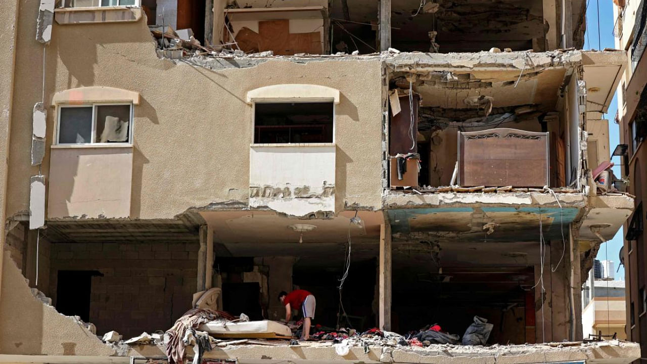 A Palestinian man looks for belongings to salvage in a damaged building following Israeli air strikes in Gaza. Credit: AFP Photo