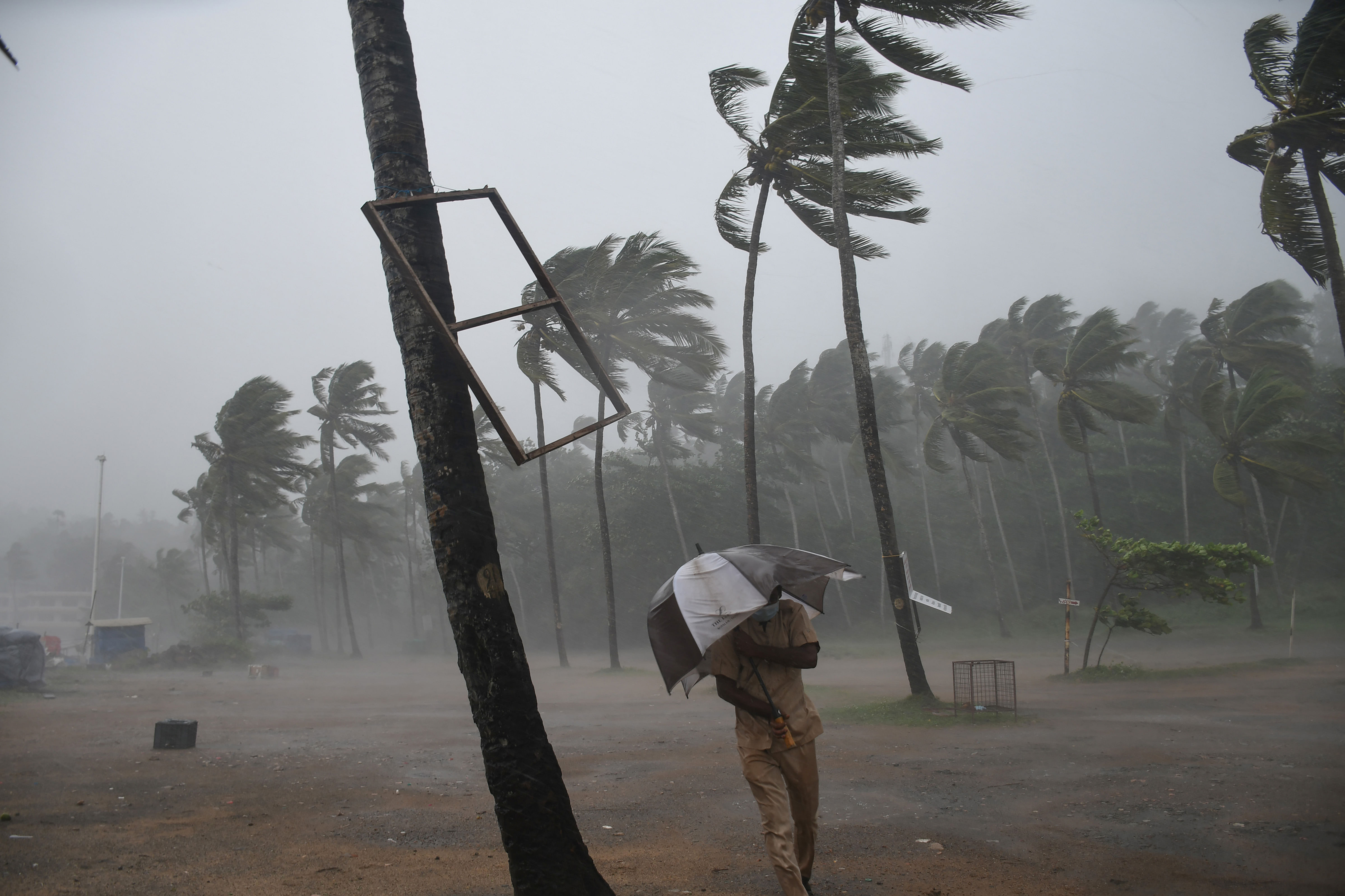 A man rushes to take cover from strong winds and heavy rain at the Kovalam coast in Thiruvananthapuram. Credit: PTI Photo