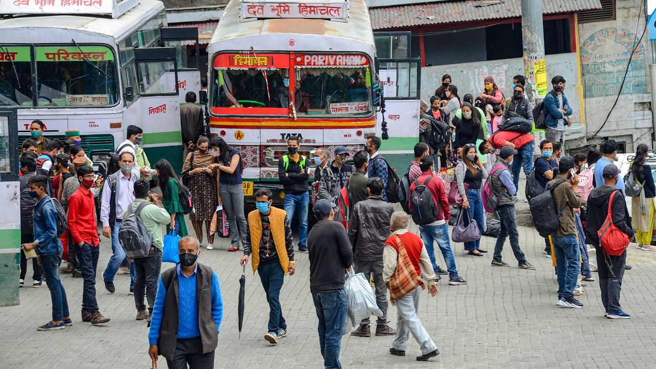 People wait to board buses to leave for their native places ahead of imposition of the curfew to contain the spread of Covid-19, in Shimla. Credit: PTI Photo