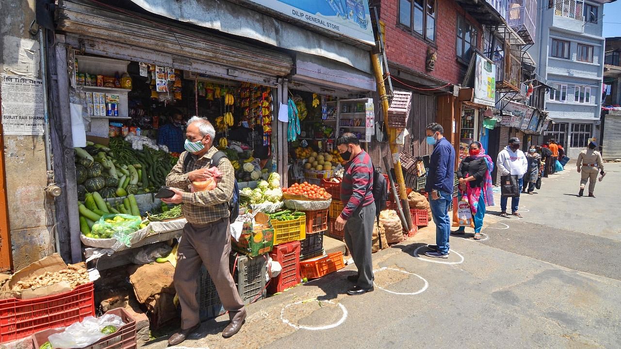 People follow social distancing norms to buy essential items during ongoing Covid-19 curfew, at a market in Shimla. Credit: PTI Photo