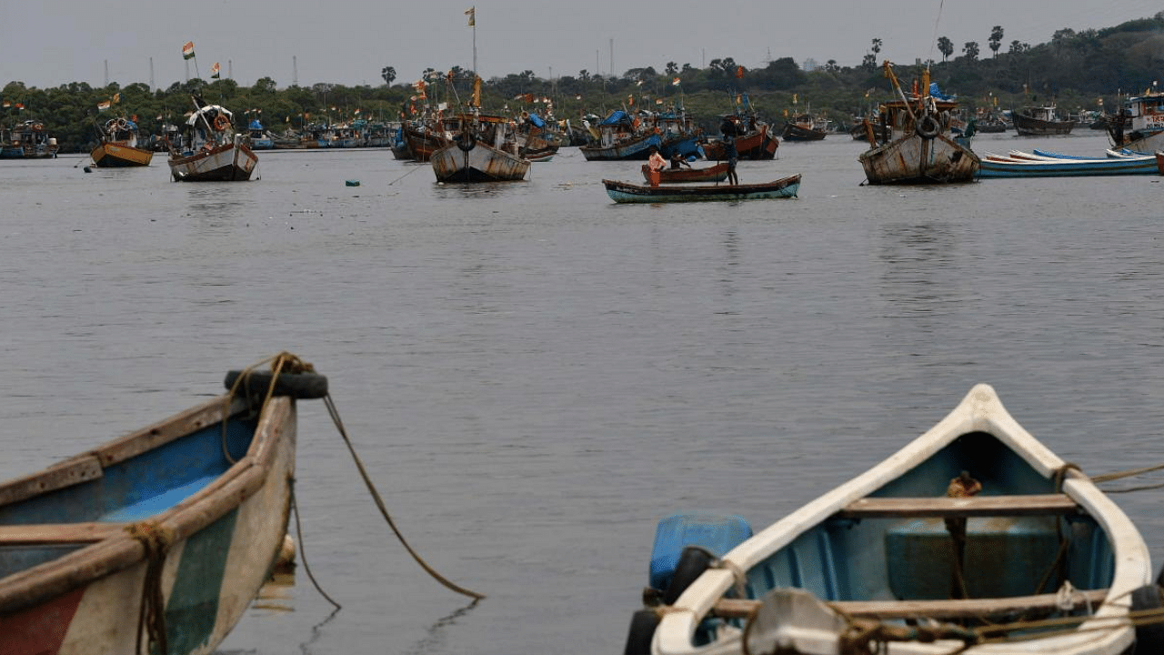 Boys row a boat near moored fishing boats at a fishing village off the city coast in the wake of the impending cyclone Tauktae in Mumbai. Credit: AFP Photo