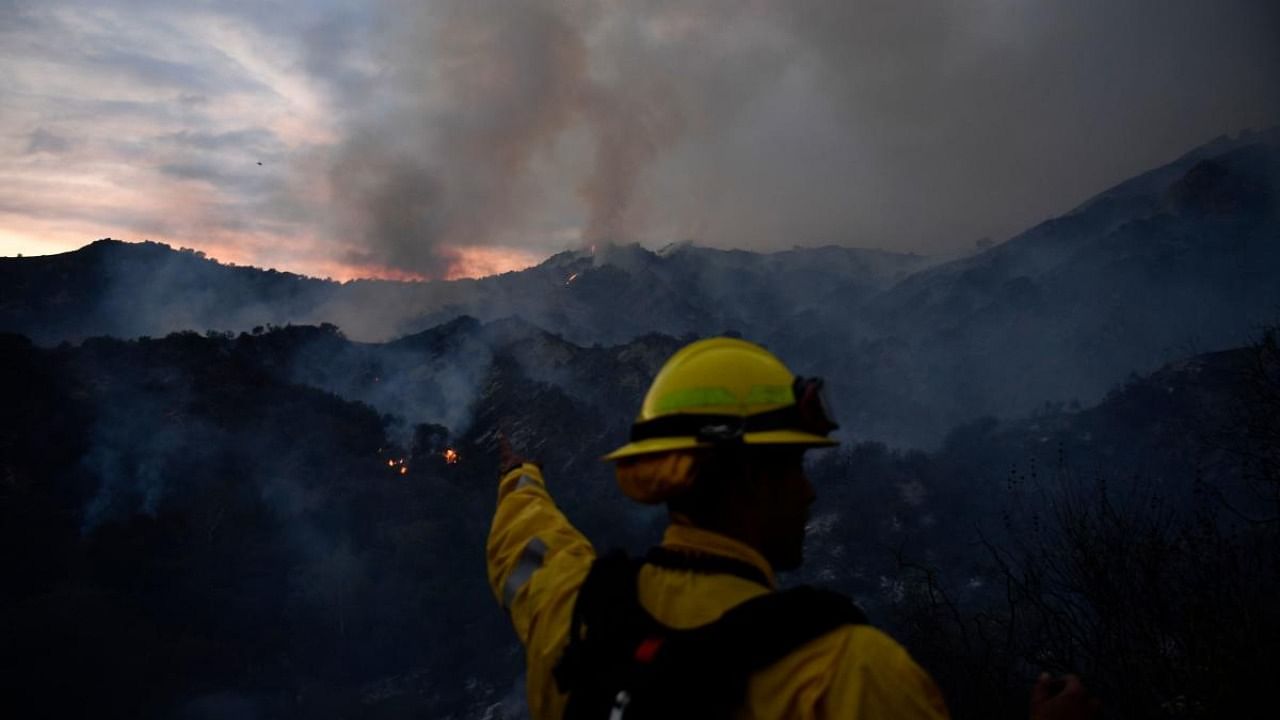 A firefighter looks at the flames from the Palisades fire cresting the hills in the distance in Topanga State Park, North West of Los Angeles. Credit: AFP Photo