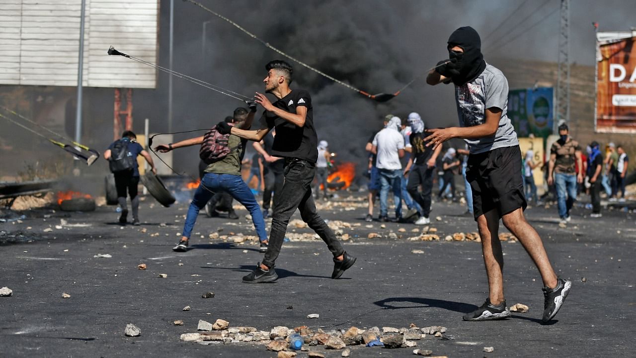 Palestinian protesters use slingshots to hurl stones at Israeli security forces amid clashes near the settlement of Beit El and Ramallah in the occupied West Bank, on May 17, 2021. Credit: AFP Photo
