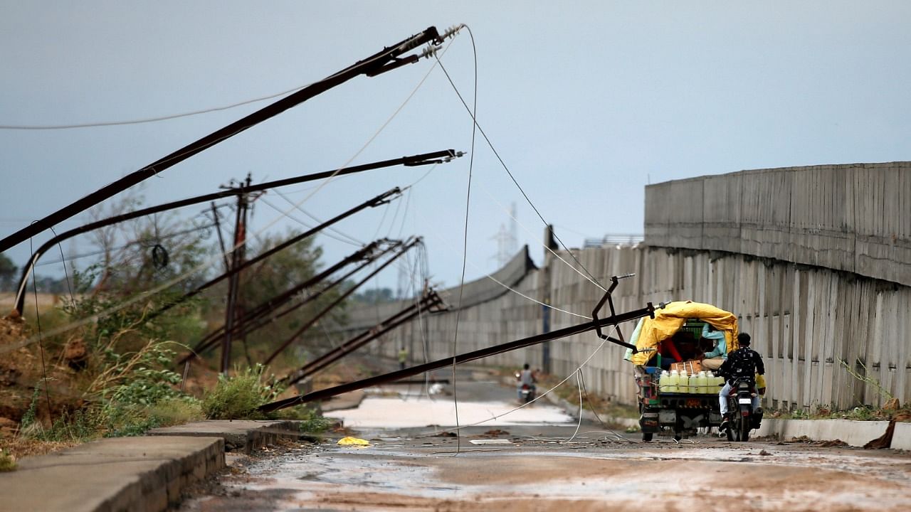 People move past electricity poles damaged by cyclone Tauktae, near Una, in the western state of Gujarat. Credit: Reuters Photo