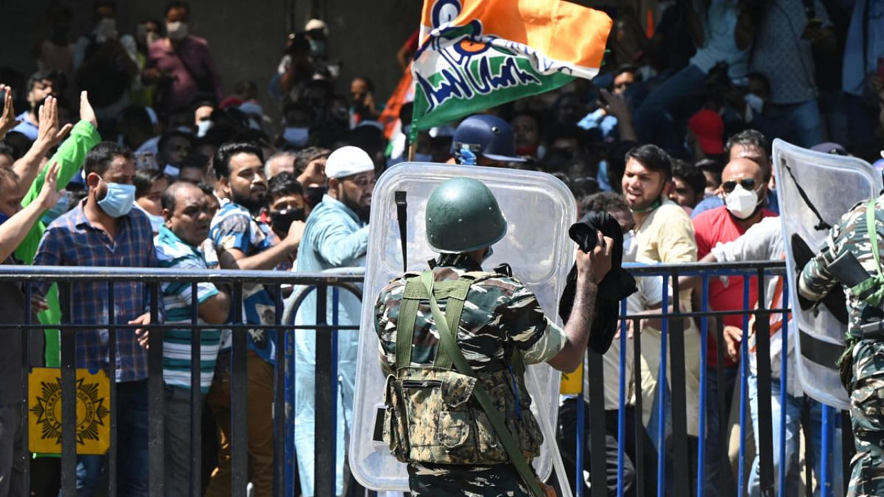A paramilitary personnel stands guard at the gate of the Central Bureau of Investigation (CBI) office as Trinamool Congress (TMC) supporters shout slogans. Credit: AFP Photo