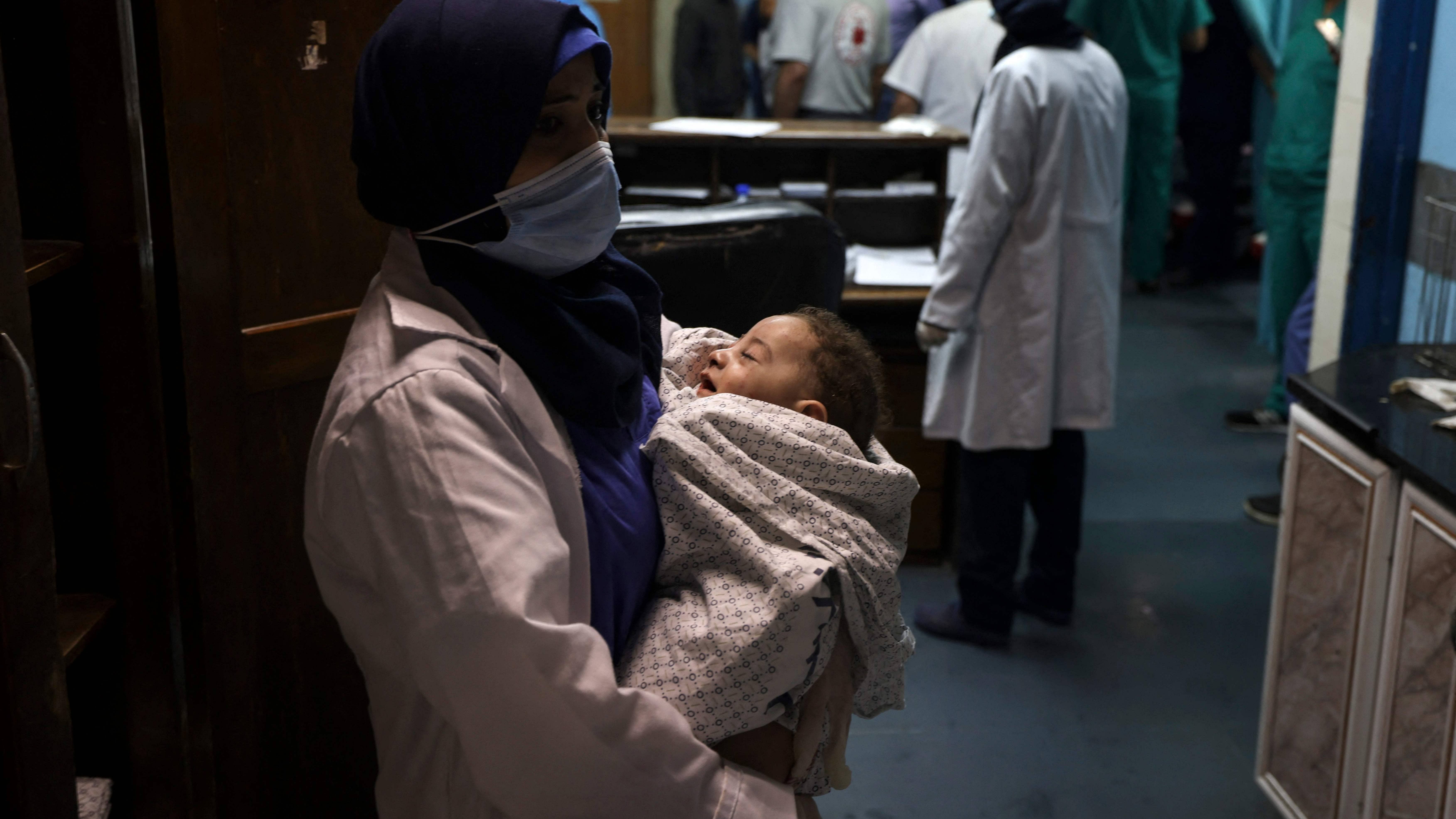 A nurse holds a baby, who was pulled alive from under the rubble while seven other family members perished, at Al-Shifa Hospital, after an Israeli air strike struck al-Shati Refugee Camp without advance warning during the night, in Gaza City early on May 15, 2021. Credit: AFP