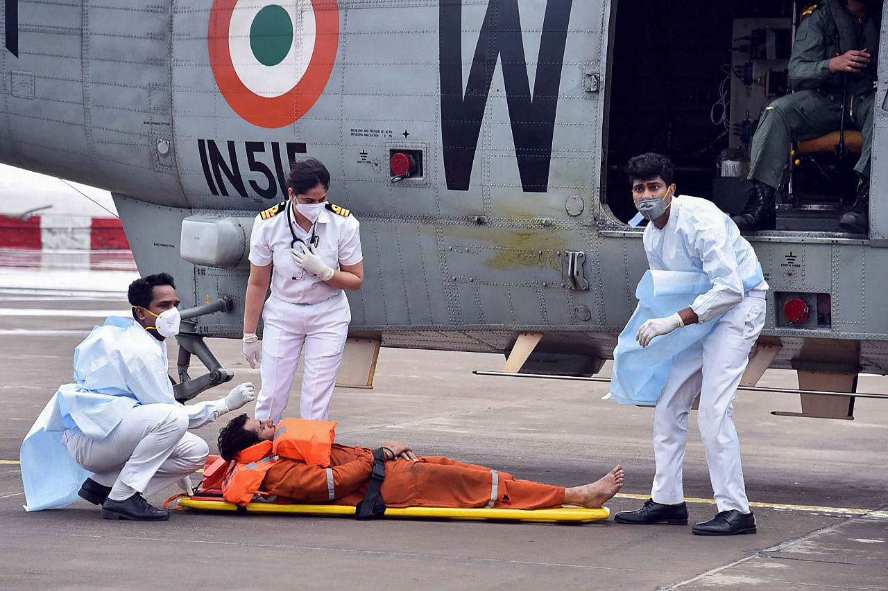 Naval personnel help an injured worker rescued from an offshore barge, which had gone adrift amidst heavy rain and strong winds due to Cyclone Tauktae, after being airlifted on an Indian Navy Seaking helicopter for medical attention at INS Shikra in Mumbai. Credit: Indian Navy/AFP