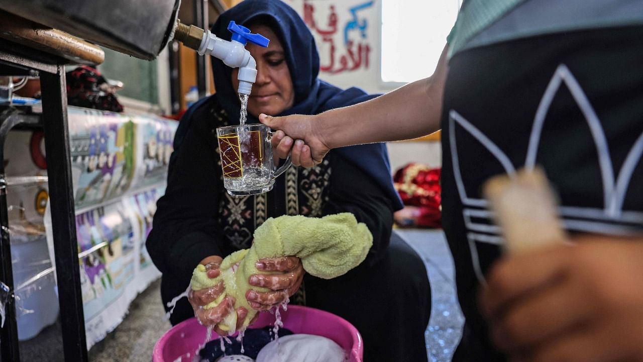 A displaced Palestinian woman washes her family's laundry at a school run by the United Nations Relief and Works Agency for Palestinian Refugees (UNRWA) in Gaza City on May 18, 2021. Credit: AFP Photo