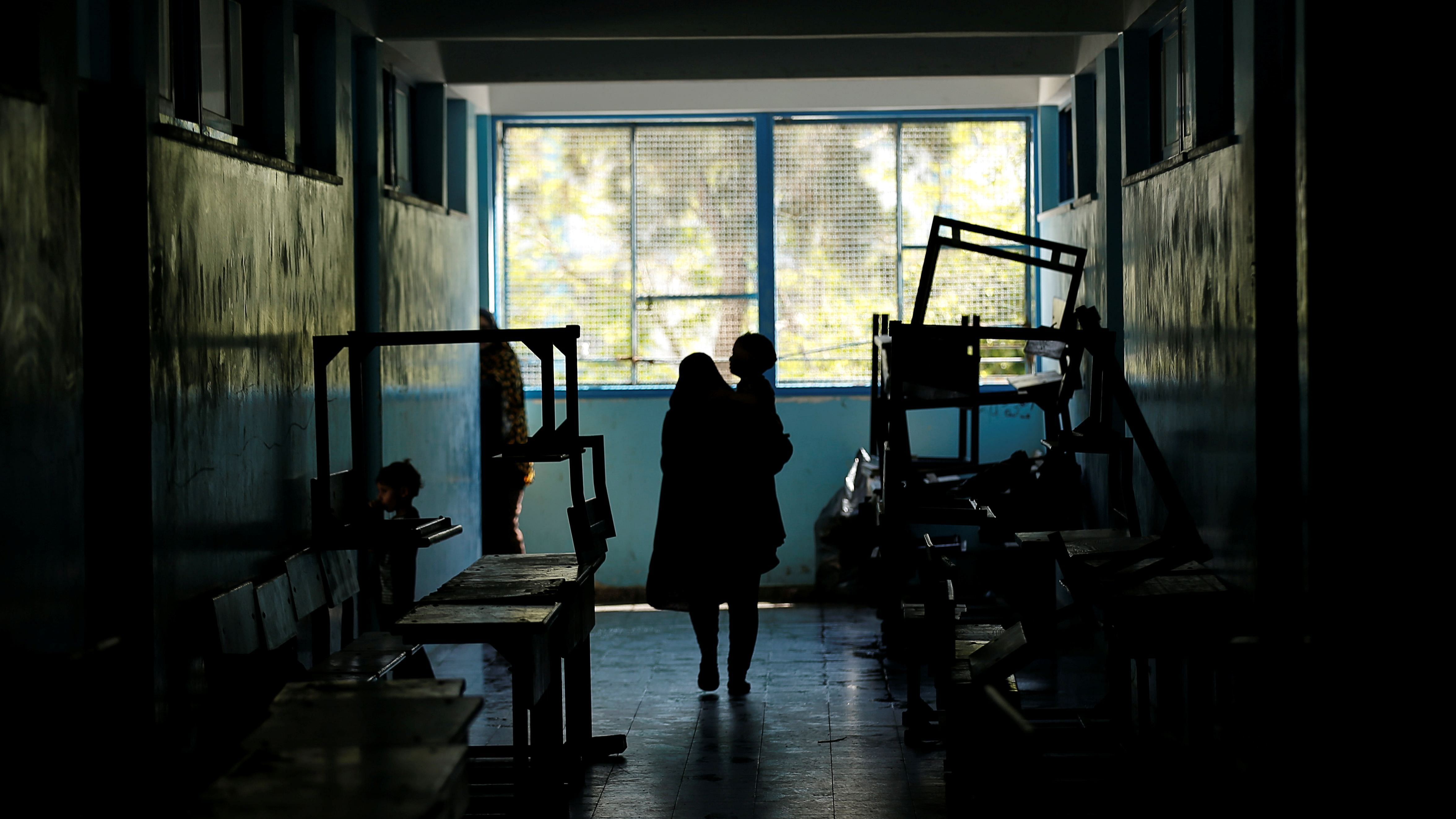 A Palestinian woman, who fled her home due to Israeli air and artillery strikes, carries her child as she walks at a United Nations-run school where they take refuge, in Gaza City May 15, 2021. Credit: Reuters Photo/ Suhaib Salem