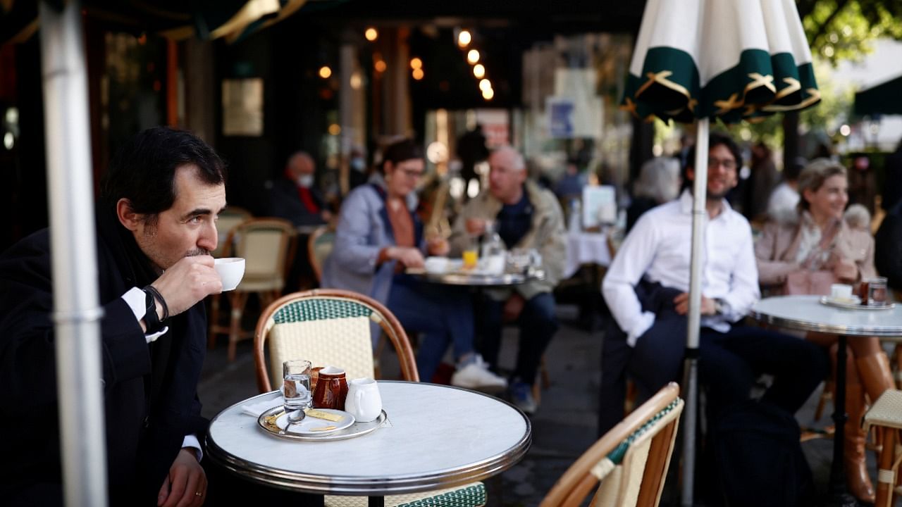 A customer enjoys a drink at the terrace of the cafe and restaurant Les Deux Magots, as cafes, bars and restaurants reopen their terraces after closing down for months, amid the coronavirus disease (Covid-19) outbreak, in Paris, France, May 19, 2021. Credit: Reuters Photo