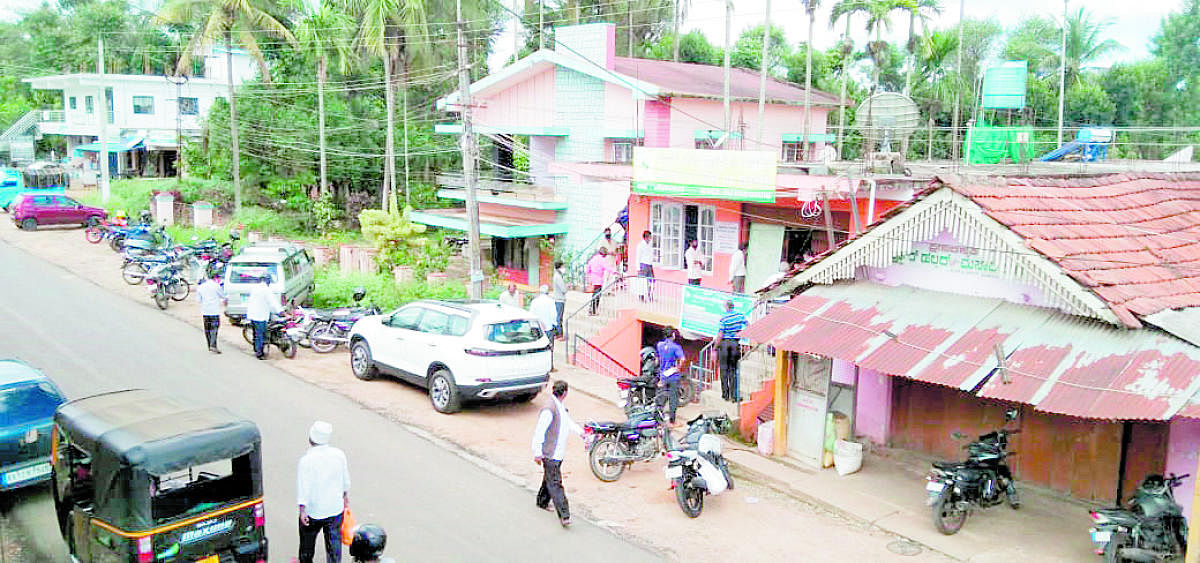 People wait in a queue in front of the District Central Cooperative Bank on Shanivarasanthe-Hosur Road.