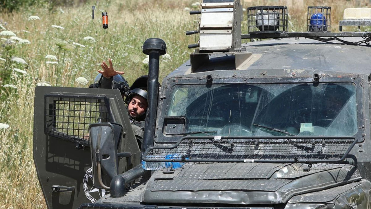 A member of the Israeli security forces tosses a sound bomb to ward off onlookers and journalists at the entance of the Salem base near the West Bank town of Jenin. Credit: AFP Photo