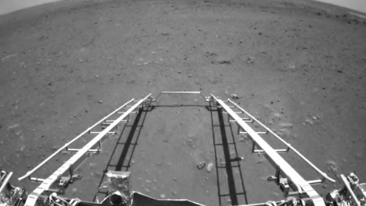 This picture released on May 19, 2021, by the China National Space Administration (CNSA) via CNS shows an image taken by the front obstacle avoidance camera of China's Zhurong rover, facing the rover's direction of movement and showing the deployment of the ramp mechanism, on the surface of Mars, after it landed on Mars on May 15, 2021. Credit: AFP Photo
