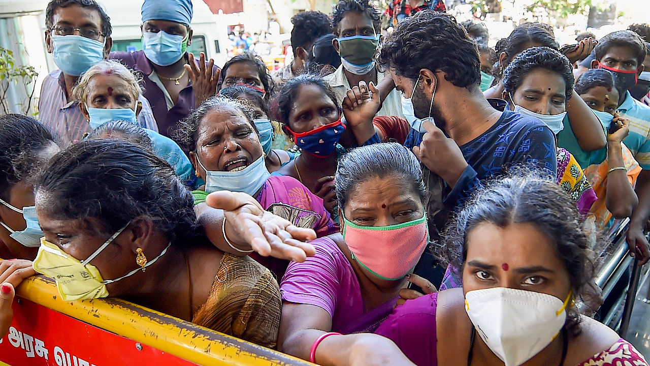 Attenders of Covid-19 patients stand behind a police barricade at Covid-19 care centre of the Rajiv Gandhi Government General Hospital in Chennai. Credit: PTI Photo